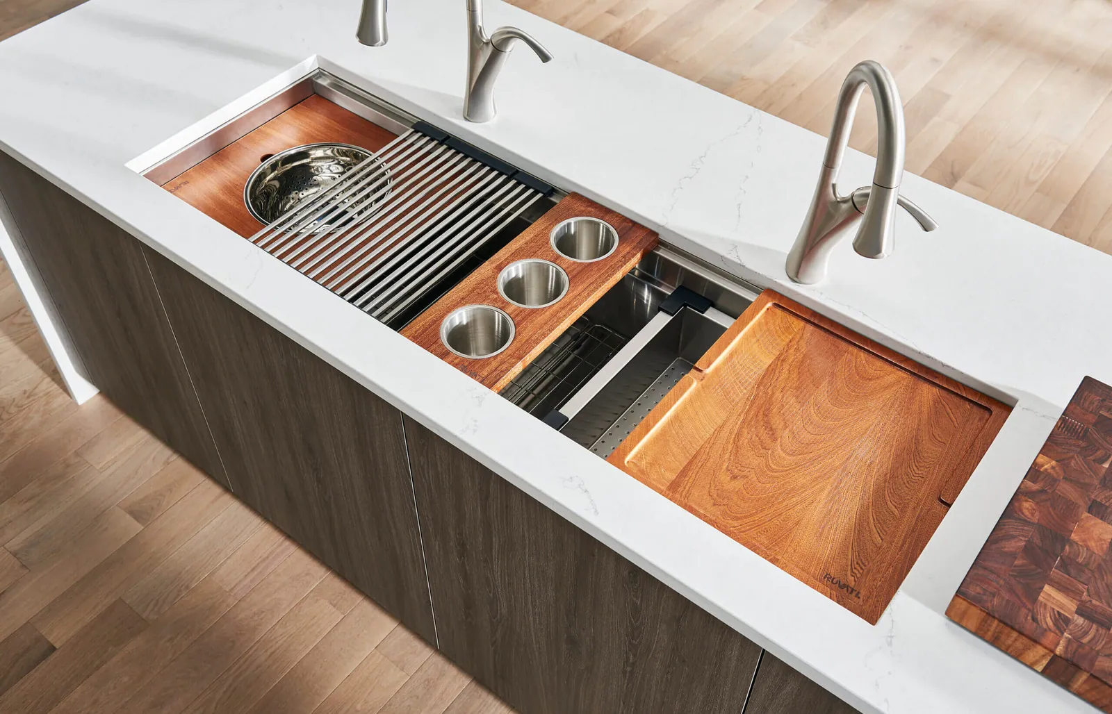 A workstation sink with the cutting board, colander and drying rack in their ledge